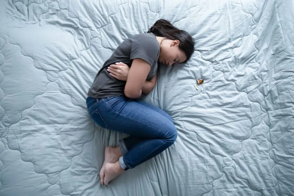A young female laying on her side on the bed next to methaqualone drugs used to induce sedation.