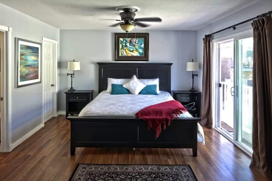 Residential bedroom of our Orange County rehab homes with hardwood floors, nice bed, patio