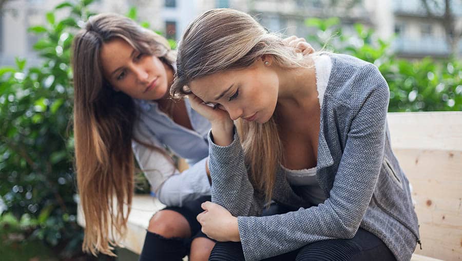 A woman comforts her friend who has been drinking a lot, showing why early intervention matters