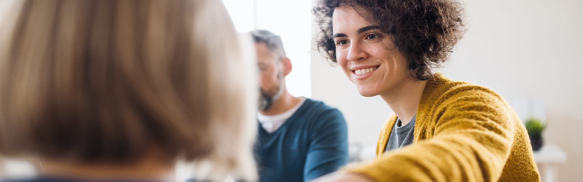 Woman with short curly hair consoling another woman in group therapy