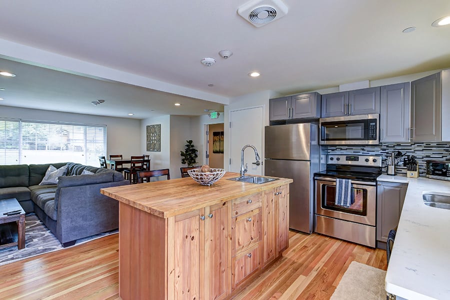 Modern kitchen in inpatient rehab with wood island, stainless steel appliances, and wood floors