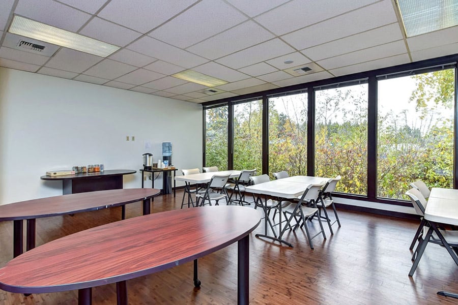 Event room with large tables and chairs, huge windows with trees on the outside 