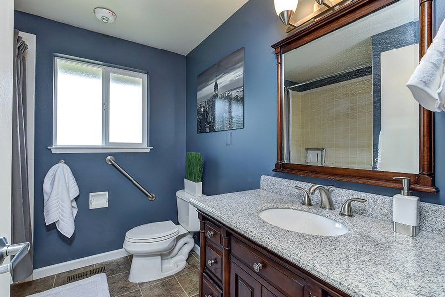 Modern bathroom with blue walls, vanity, and tile floors 