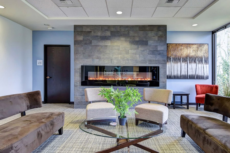 Large, modern sitting  room with fireplace, chairs and glass table