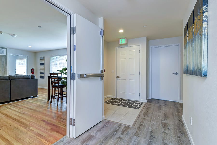 Modern inpatient rehab with dining table, wood floors, and front door