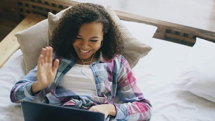 A girl is video chatting online with a friend to help with feelings of isolation and preventing relapse during the pandemic. 