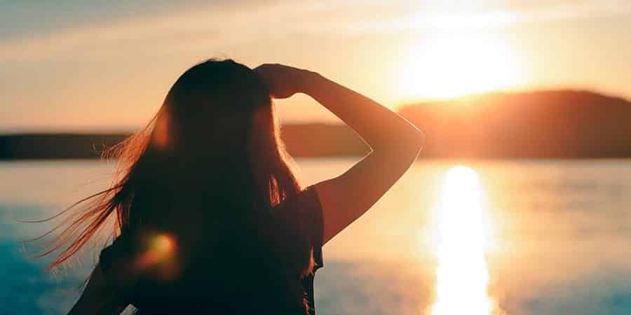 A silhouette oh a woman who is in rehab watching the beach sunset 