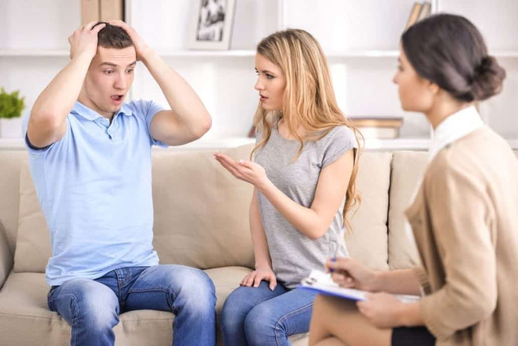 A family sets up an intervention for a male family member who looks visibly shocked by the confrontation.
