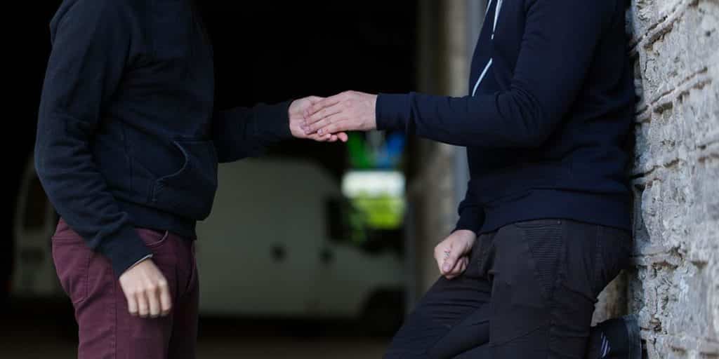 Two men exchanging opioid drugs on the street during the covid 19 pandemic. 