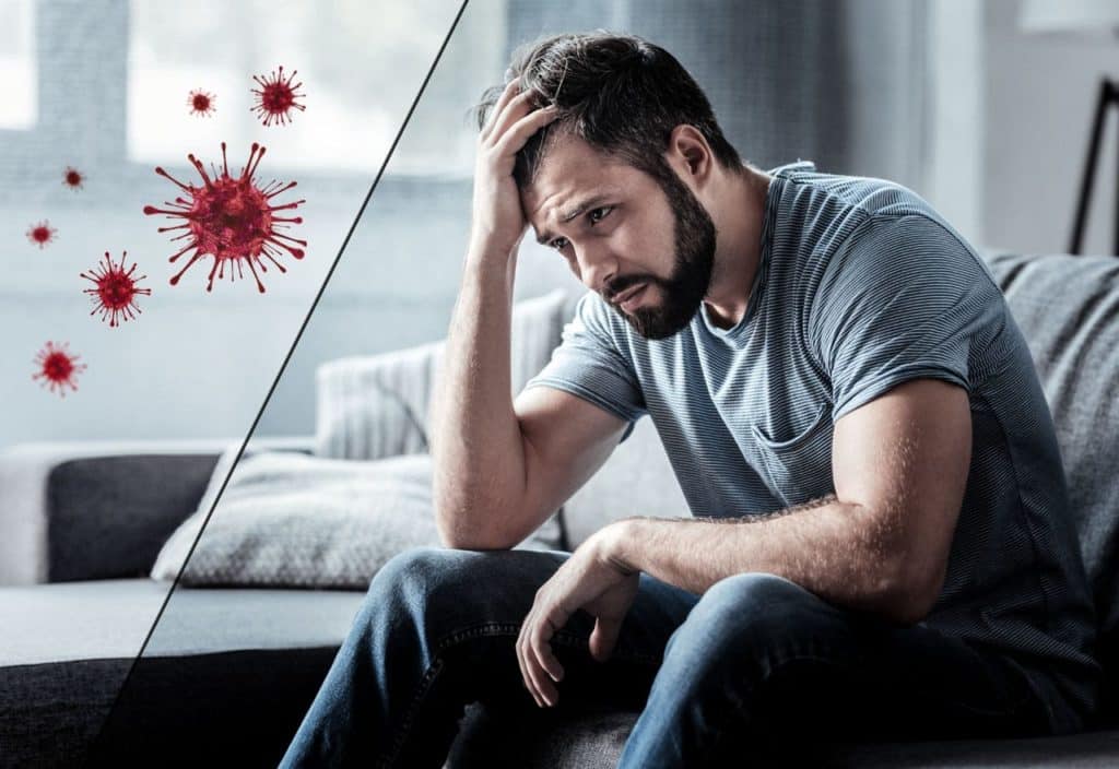 A man suffering from depression is sitting on the sofa contemplating depression treatment during the covid 19 pandemic. 