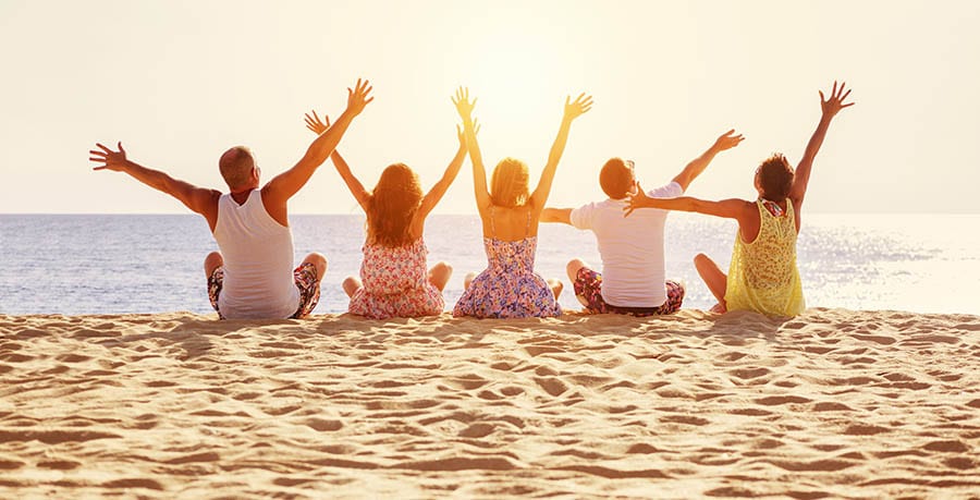 A group of friends are sitting on the sand at the beach celebrating their recovery. 