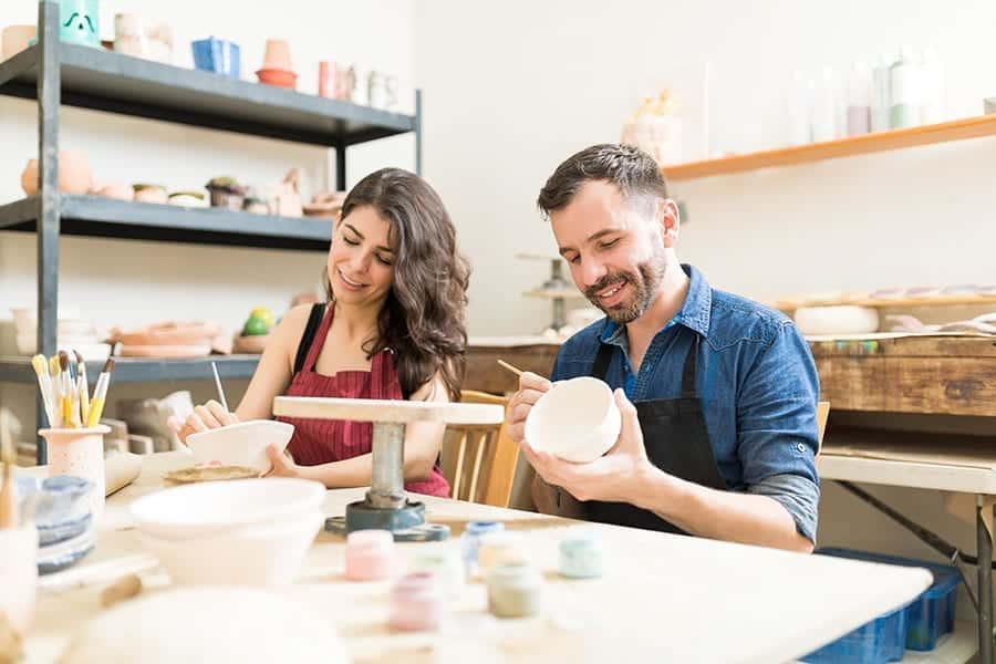 A young couple in a pottery class painting bowls as an activity to help prevent relapse.
