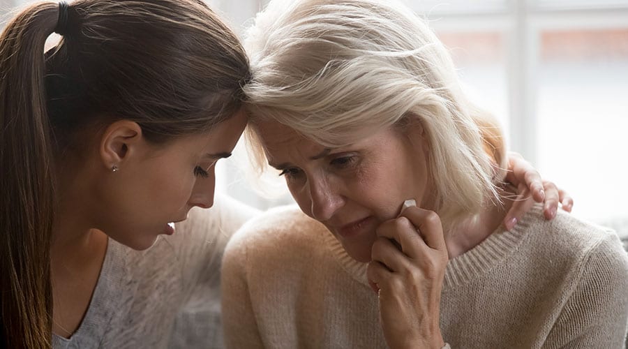 Two women comfort each other as they suffer from grief and loss of a loved one.