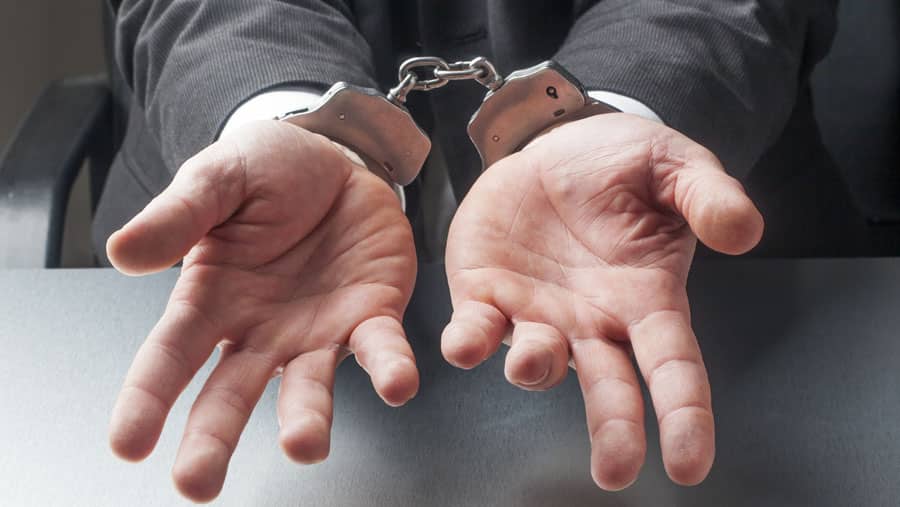 A person’s wrists are handcuffed representing which treatment works better for addiction, incarceration or rehabilitation. 