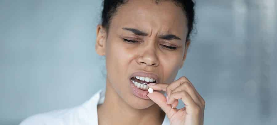 A woman in sobriety relapses on prescription medication as she begins to take a pill. 