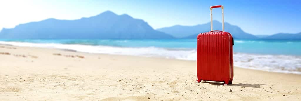 A red suitcase on the beach represents an inpatient rehab facility for alcohol addiction. 