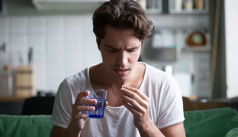 A young man preparing to take pill medication and is unaware he is self-medicating with drugs. 