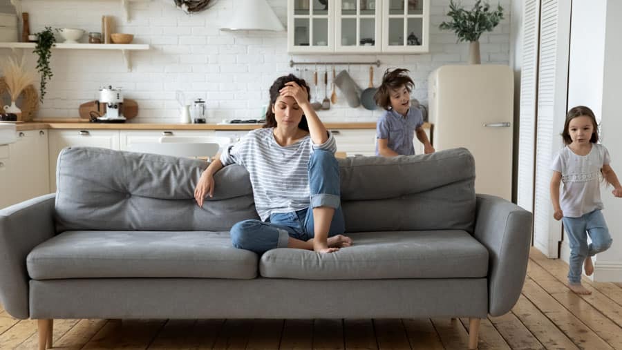 Two young children running around the house surround a mother struggling with mental health during quarantine. 