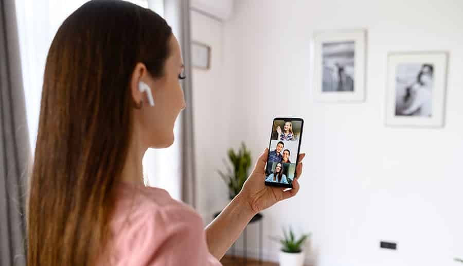 A woman video chatting with members of her addiction support group on her phone during the covid 19 pandemic. 