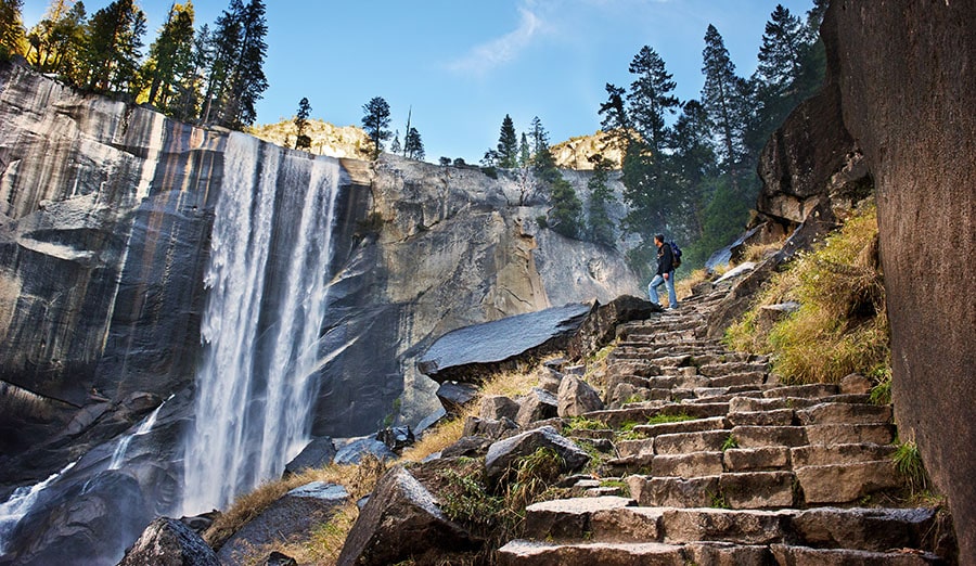 A person is on a nature hike overlooking a waterfall because it can be beneficial for mental health during quarantine. 