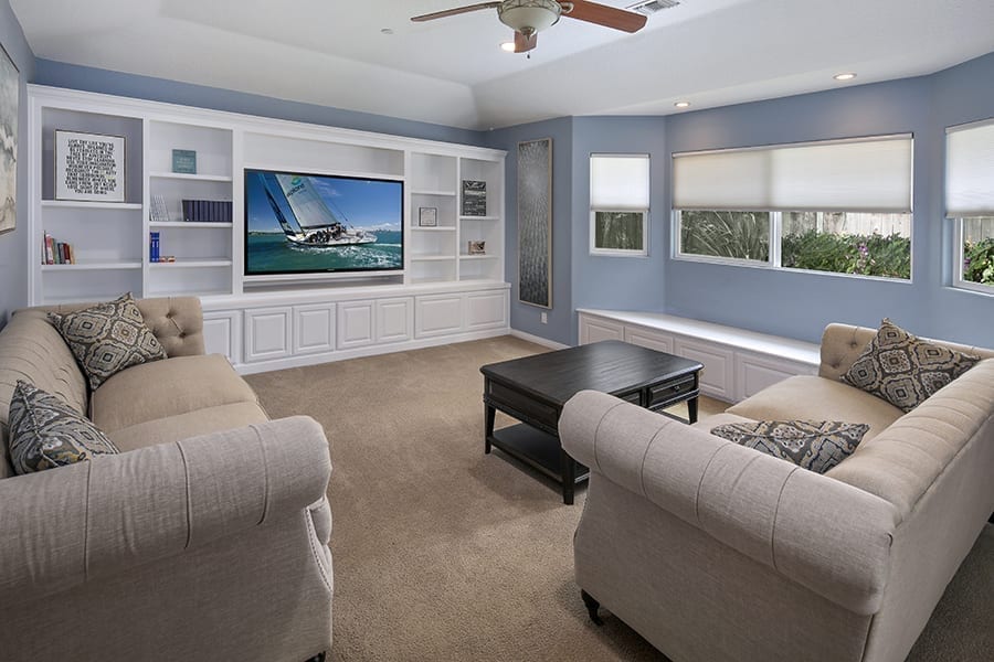 Modern living room with grey couch, bay window, tv, and blue walls in residential rehab