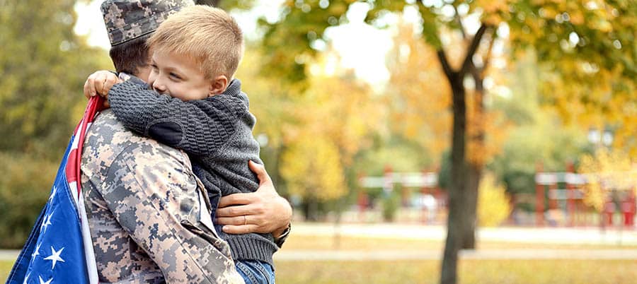 A young boy hugs his father who is a military serviceman. 