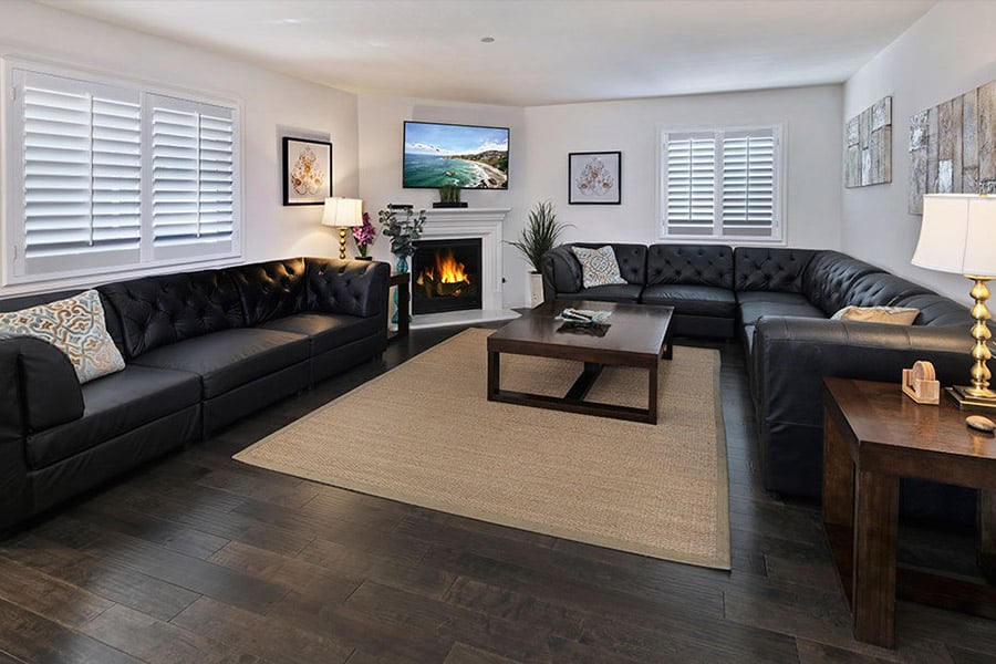 Brightly lit room with black couches, tv,  and fireplace