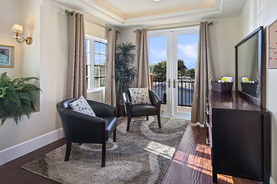 brightly lit, sunny room with balcony to blue skies. Dark leather chars on a tan rug