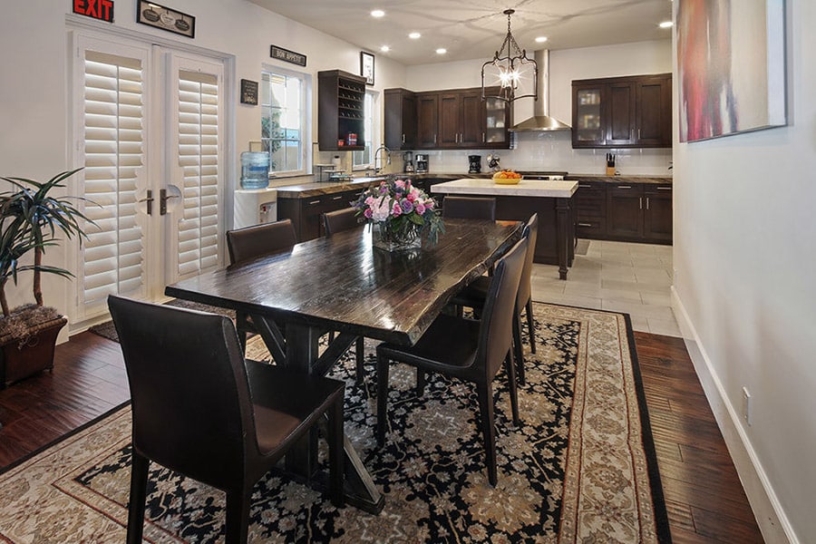 Clean, beautifully designed kitchen with stove, cabinets, island in the back. Dark wooded floors and matching table with chairs