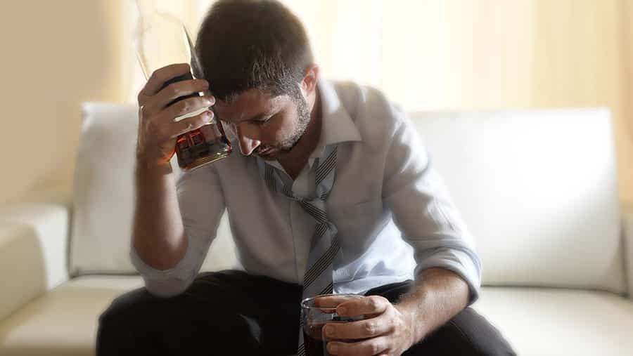 Man with bottle of alcohol contemplates how to stop drinking during the Covid-19 pandemic.