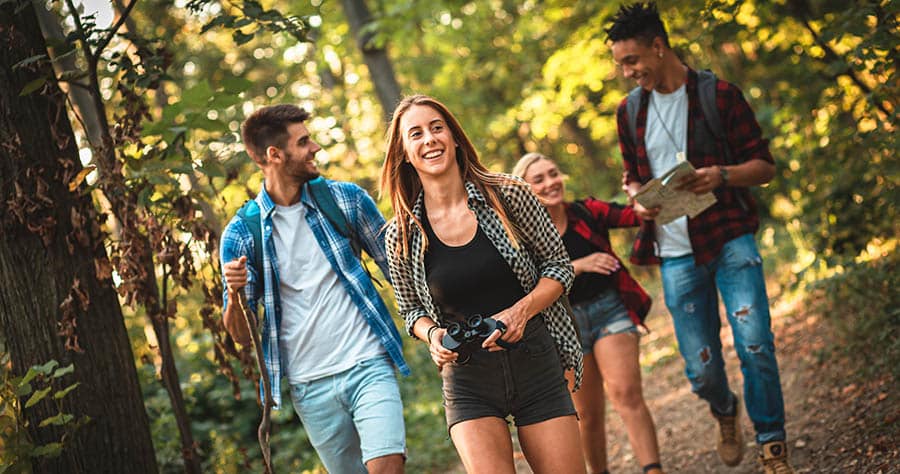 A group of friends is hiking through the woods and creating healthier new habits to reduce alcohol cravings. 