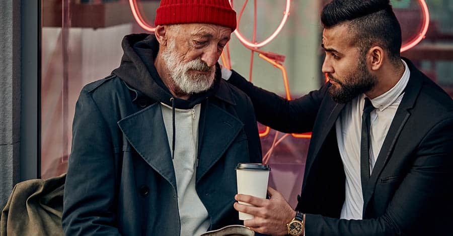 A young man is showing compassion to an older gentleman who is suffering from addiction as a form of harm reduction. 