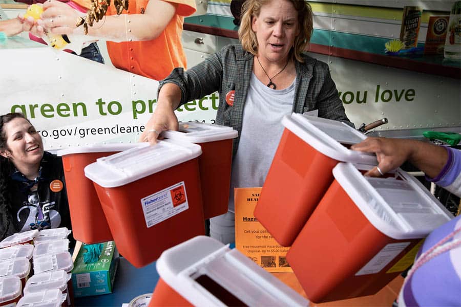 People drop off used Injection needles and pick up free sharps disposal containers at an event in Portland, OR.