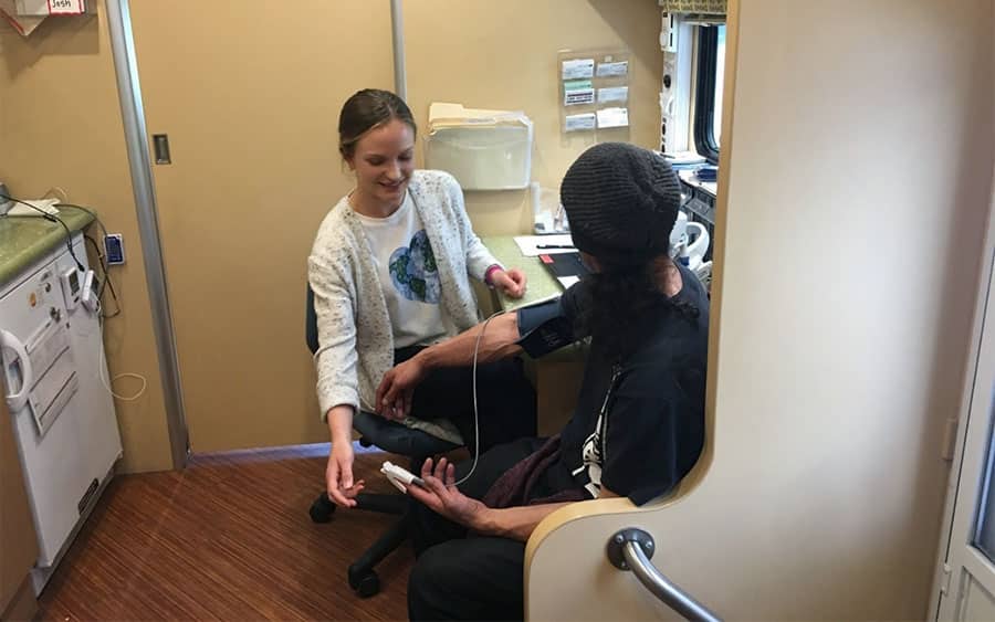 A man gets his vitals taken at a mobile medical clinic as a part of harm reduction for addiction.   