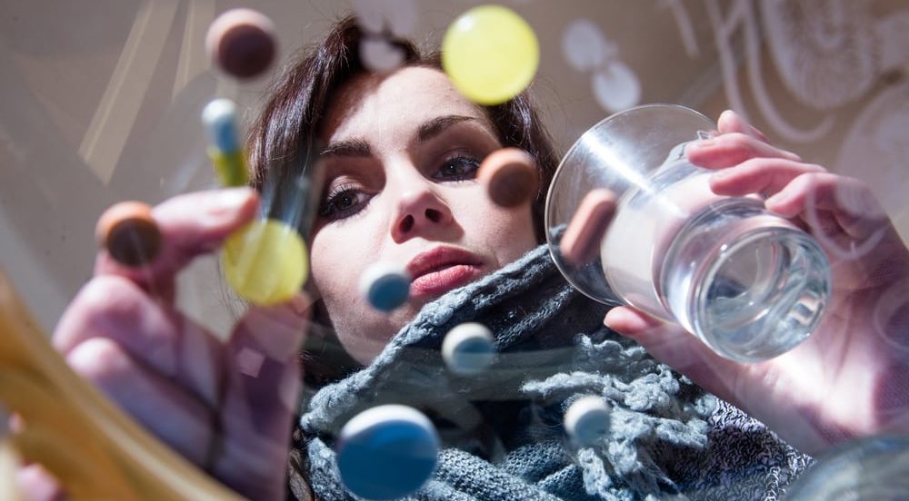 Woman staring at pills contemplating if she should take them