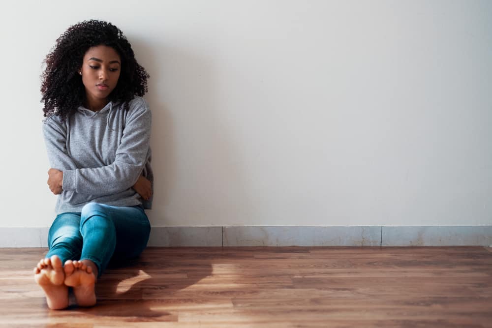 Girl sitting alone on the floor suffering from trauma and substance abuse disorder