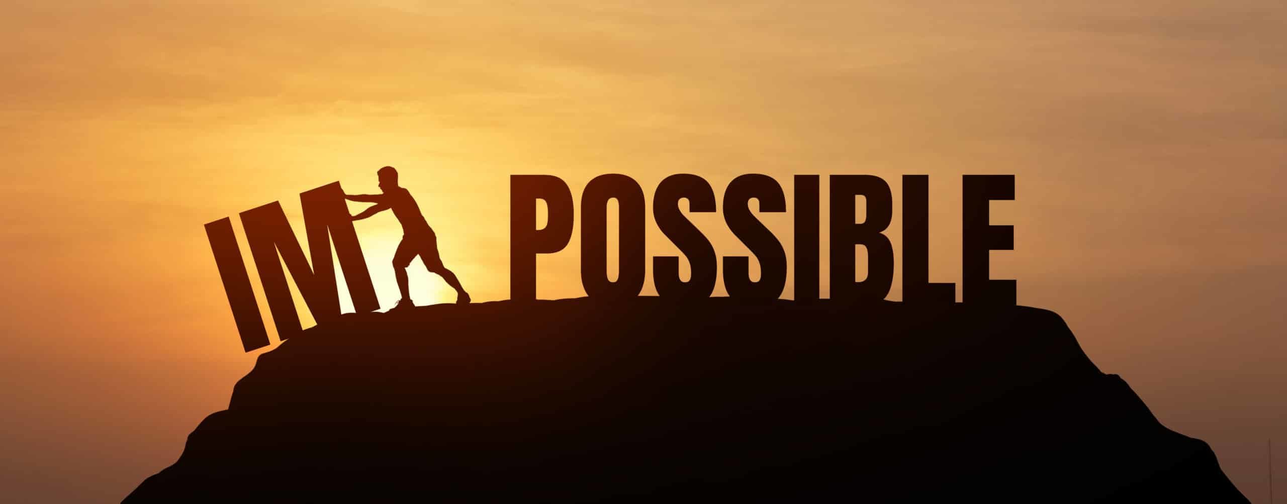Side profile of person separating the word "impossible" between the M and P to say "Im Possible" while standing on a mountain with the sunsetting behind it
