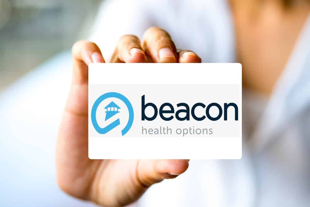 Woman holding beacon insurance rehab coverage card