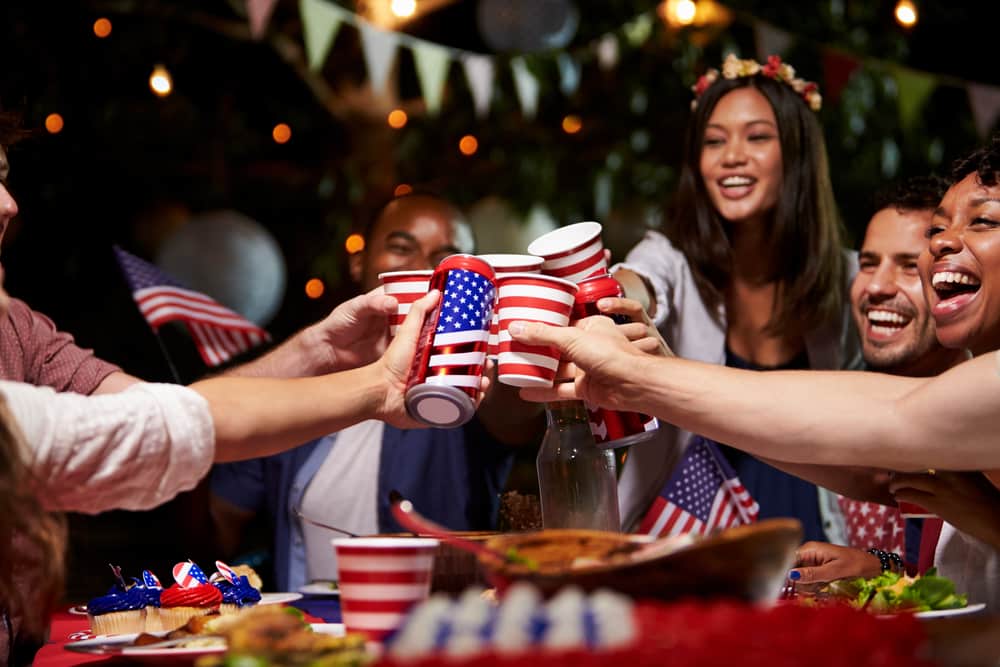 A group of young adults celebrate with alcoholic beverages to celebrate the Fourth of July.