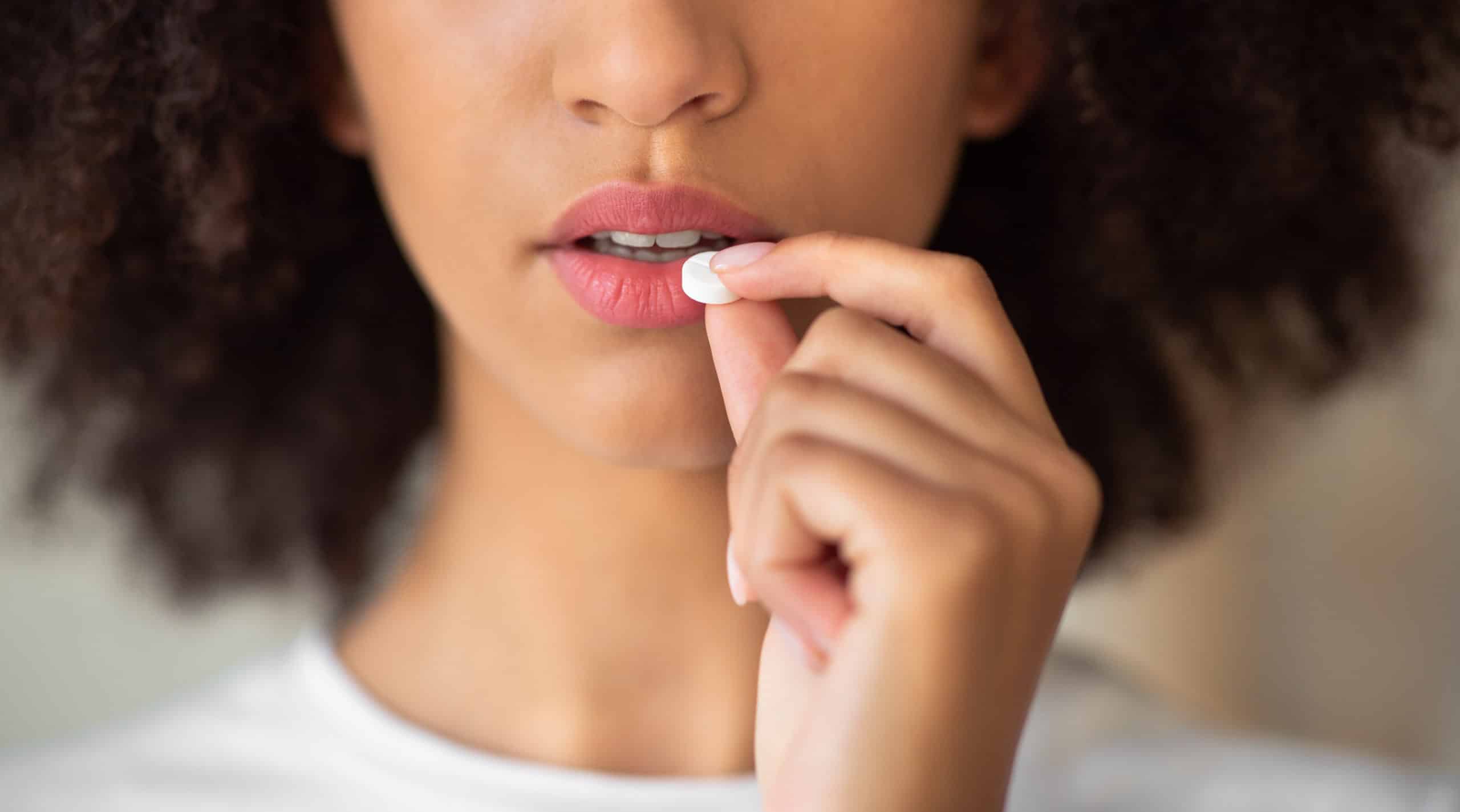 Woman suffering from adderall addiction holding a pill near her mouth contemplating if she should take it