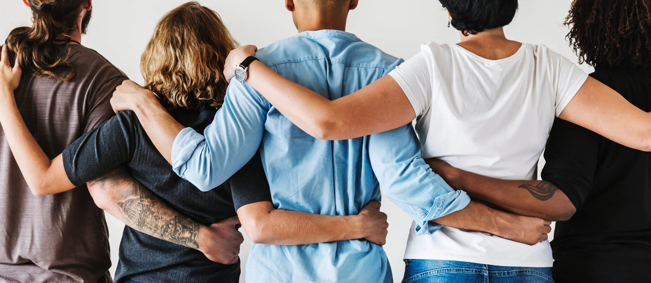 Backs of people with arms around each other in supportive stance