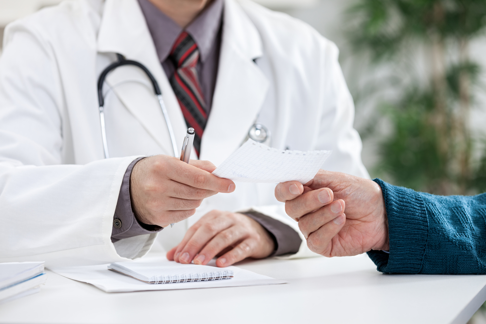 Bust of doctor handing someone a prescription on a note pad