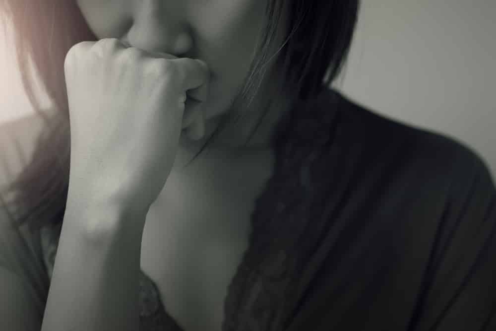 woman with mouth resting on hand, with perplexed expression in black and white 