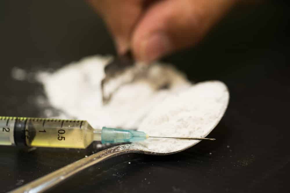 Close up of white powder heroin and syringe filled with heroin