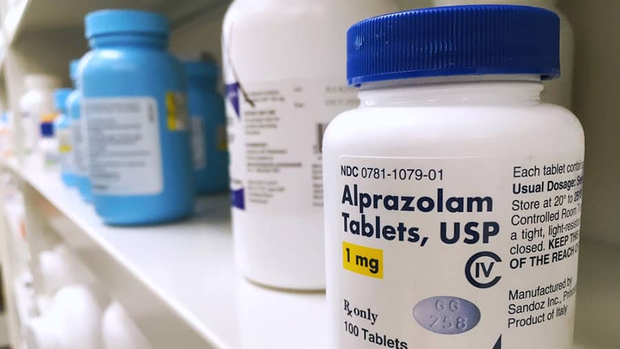 A shelf in a pharmacy stocked with various prescription medications including Alprazolam also known as Xanax. 