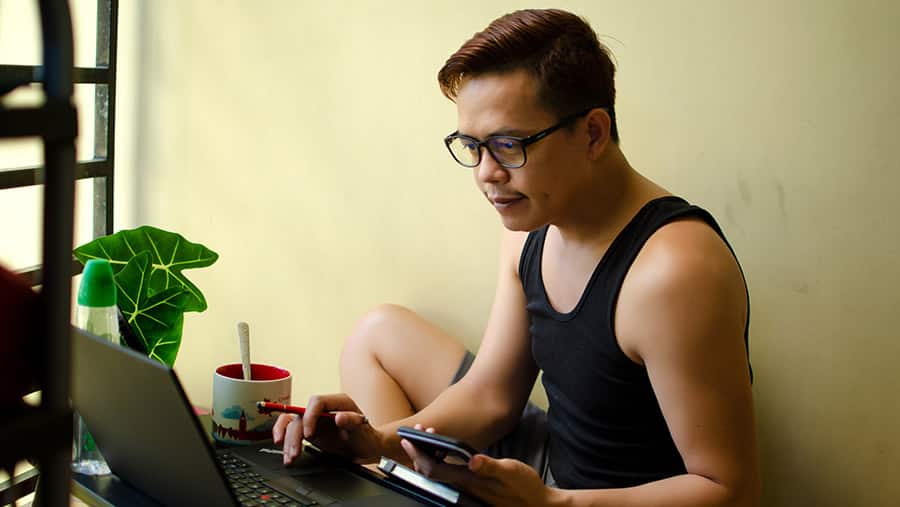 A male college student on Adderall is sitting at a table working on his laptop. 