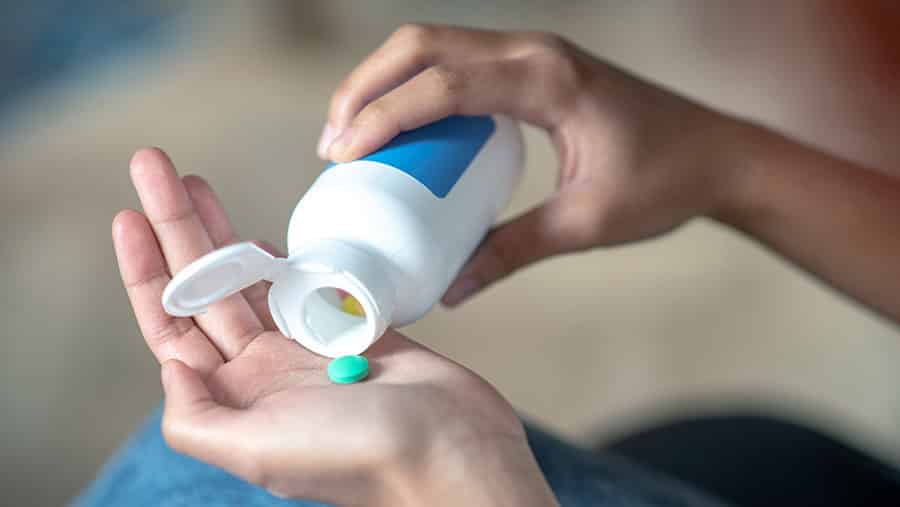 A person’s hands showing them dispense Prozac tablets from a medication bottle to contemplate Prozac interactions with alcohol and marijuana. 