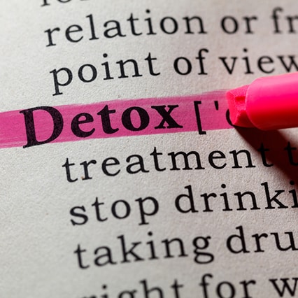 Close up a dictionary with the word "detox" being highlighted with pink marker