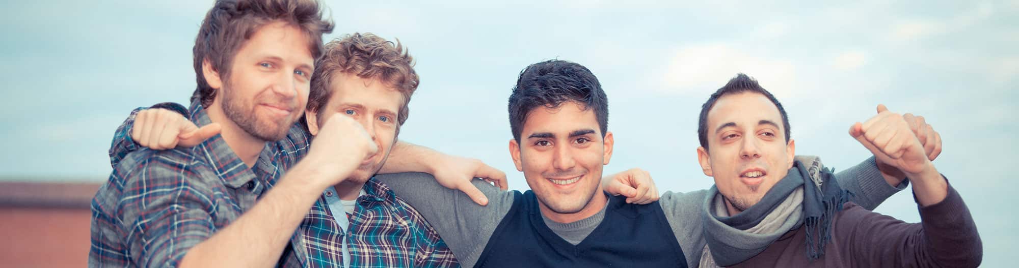 Four men with hands on each other shoulders, supporting each other through addiction treatment in Orange County