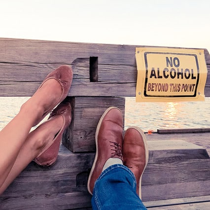 Young woman's and young man's feet rested on a fence near the ocean at a sober transitional living in Orange County 